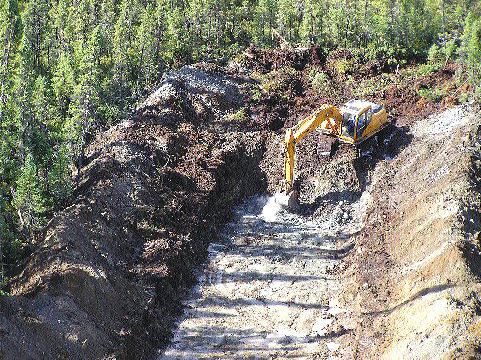 A backhoe clears MetalCorp's Pickle Lake property for subsequent trenching.