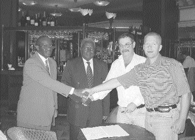 Photo by Barbara ThomaeFrom left: Kilembe Mines General Manager Robert Makoma and Kilembe Chairman Fredrick Nyakana shake hands with Uganda Gold President Al Beaton, and Uganda Gold Director Brad Jefferson. Uganda Gold recently inked a deal in Vancouver to acquire as much as a 70% interest in the past-producing Kilembe copper-cobalt mine in western Uganda.