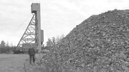 Rosaire Emond, Agnico Eagle's project manager at Goldex, stands beside a bulk sample taken from the Goldex deposit. The Goldex headframe is in the background.