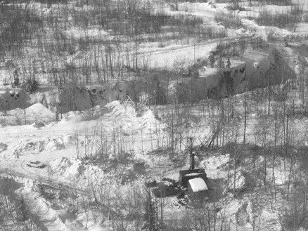 A drill at the Canadian Malartic property of Osisko Exploration operates near a glory hole of the original Canadian Malartic mine.