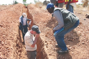 Riverstone Resources' president, Michael McInnis (left foreground), examines rock samples in a trench.