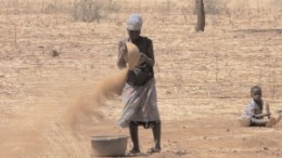 A woman pans for gold at an artisanal mine site in Burkina Faso. These primitive techniques sometimes lead to the discovery of more sizable gold deposits.