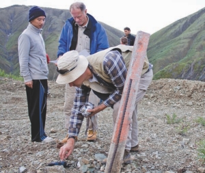 Geologist Todd McCracken (front) takes a reading at a drill hole while Prophecy Resource CEO John Lee (left) and adviser John Morganti (right) look at assay results at the Wellgreen nickel-copper-PGM project.