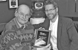 Author Chuck Davis (left) receiving the Frank Woodside Past Presidents Distinguished Service Award from Gavin Dirom (right), president and CEO of the Association for Mineral Exploration British Columbia.