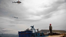 A helicopter flies above a worker at Tower Resources JD gold-silver property 300 km north of Smithers, B.C. Source: Tower Resources