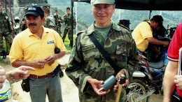 A Colombian soldier shows examples of land mines and trip wires left behind by FARC guerillas at the Angostura gold project in northeast Colombia, shortly after the army had retaken the deposit and surrounding territory in 2003. Materials such as plastic and wood are used to thwart de-mining crews' metal detectors. Photo by John Cumming