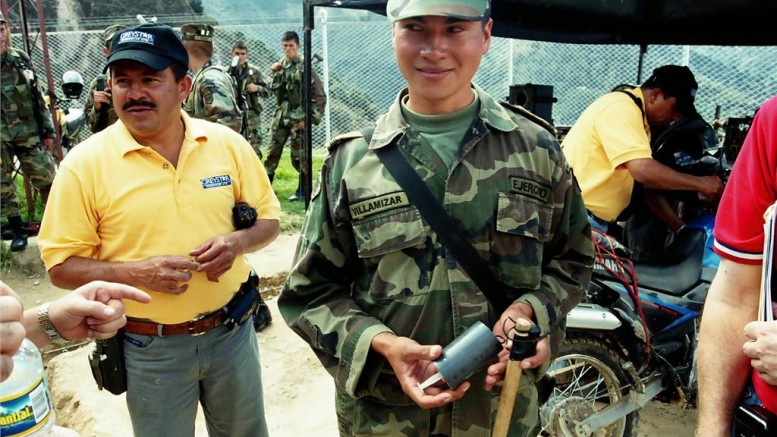 A Colombian soldier shows examples of land mines and trip wires left behind by FARC guerillas at the Angostura gold project in northeast Colombia, shortly after the army had retaken the deposit and surrounding territory in 2003. Materials such as plastic and wood are used to thwart de-mining crews' metal detectors. Photo by John Cumming