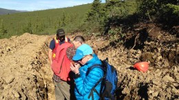 Kaminak Gold president and CEO Eira Thomas examines rock from a trench at the Coffee gold project in the Yukon. Credit: Kaminak Gold