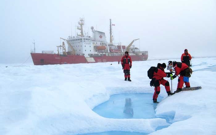 National Research Council personnel drill to measure the properties of multi-year sea ice near Banks Island in the Northwest Territories, with the Canadian Coast Guard's Amundsen icebreaker in the background. Credit: National Research Council