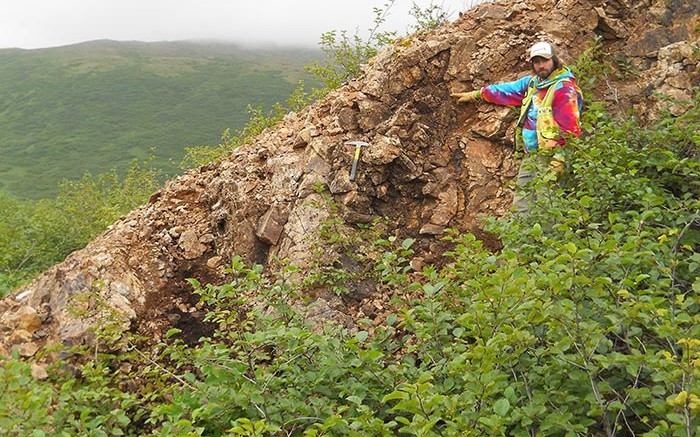 A field worker stands by the outcropping Shumagin vein at Redstar Gold's Unga gold project in Alaska. Credit: Redstar Gold