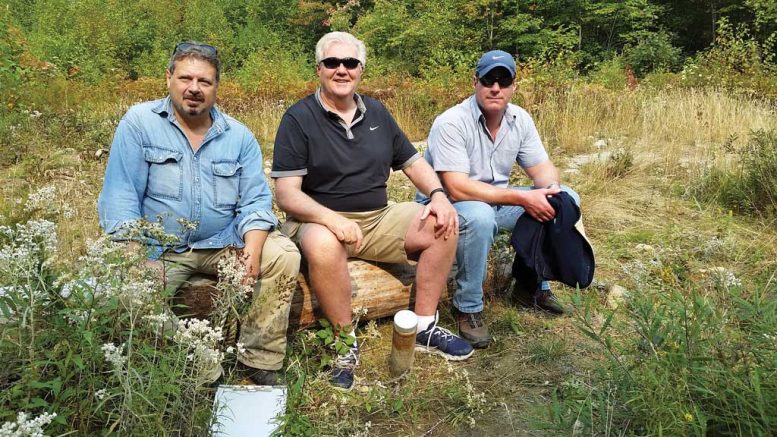 At the Pine Zone discovery hole on New Age Metal’s River Valley PGM property in northern Ontario, from left: Richard Zemoroz, project geologist; Harry Barr, founder, chairman and CEO; and Trevor Richardson, president and COO.  Photo by Trish Saywell.