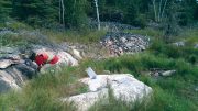 Prospector Robert Freeman sampling in 2016 at New Age Metals’ Lithium One lithium property in Manitoba. The sample bag sits on an outcrop of the Spodumene-Lepidiolite Zone. Photo by Carey Galeschuk.
